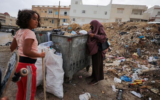 A Tunisian woman and girl look for plastic in a garbage container to earn money in Tunis July 31, 2021. (CNS/Reuters/Ammar Awad)